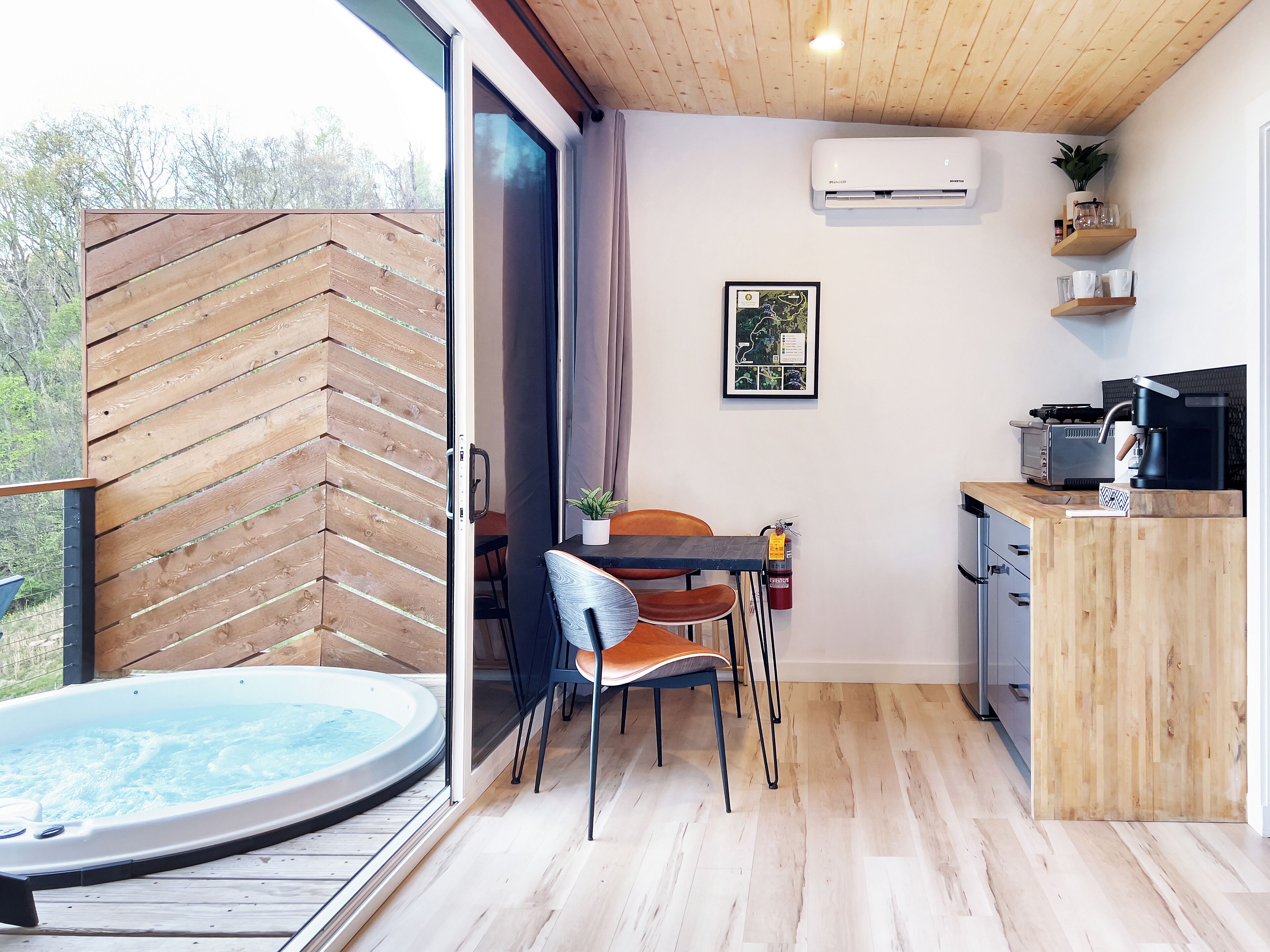 A modern kitchen with a wooden countertop, a coffee machine, and a small dining area with a table and chairs.