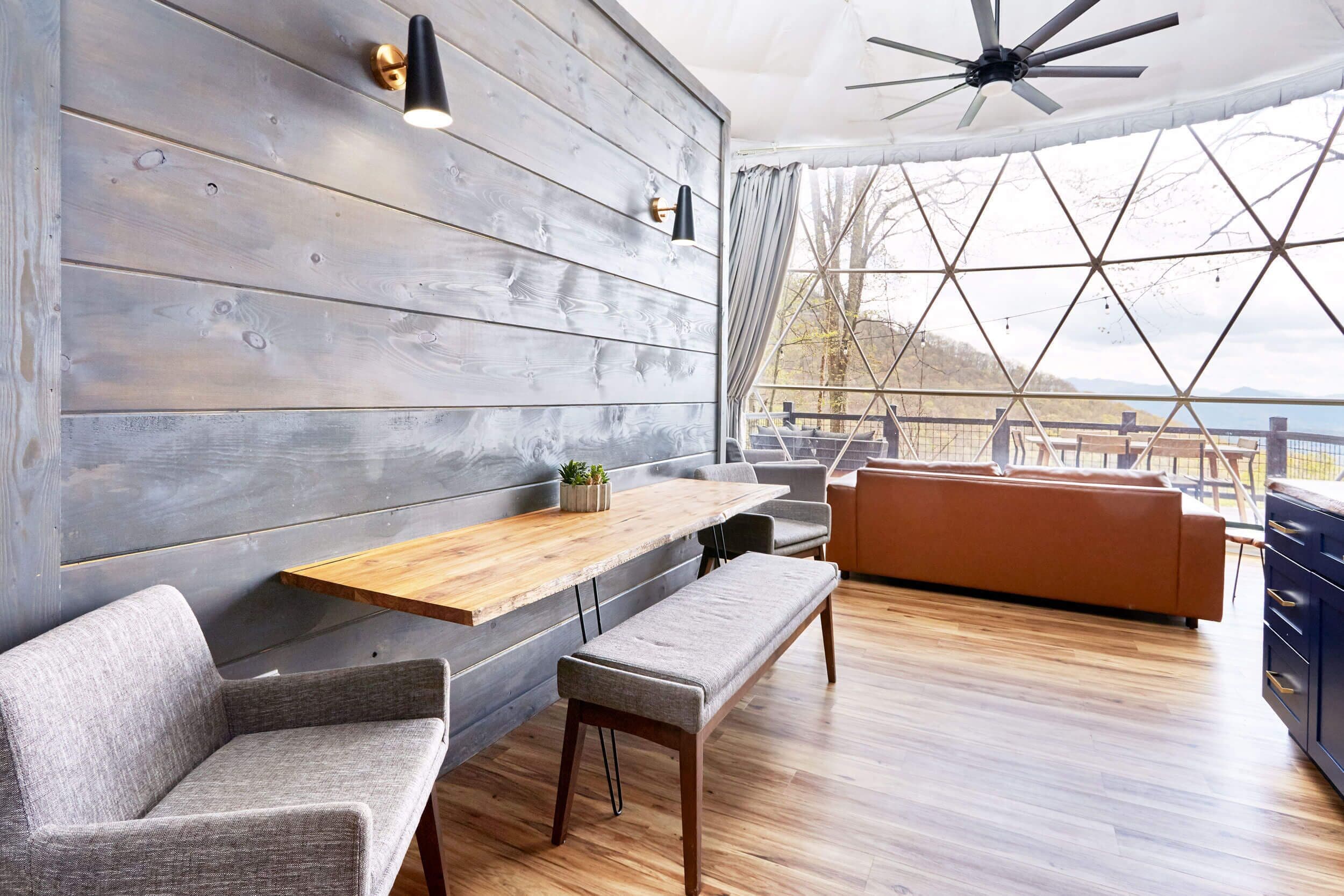 A modern interior with a wooden wall, a wooden table, a bench, and a sofa.