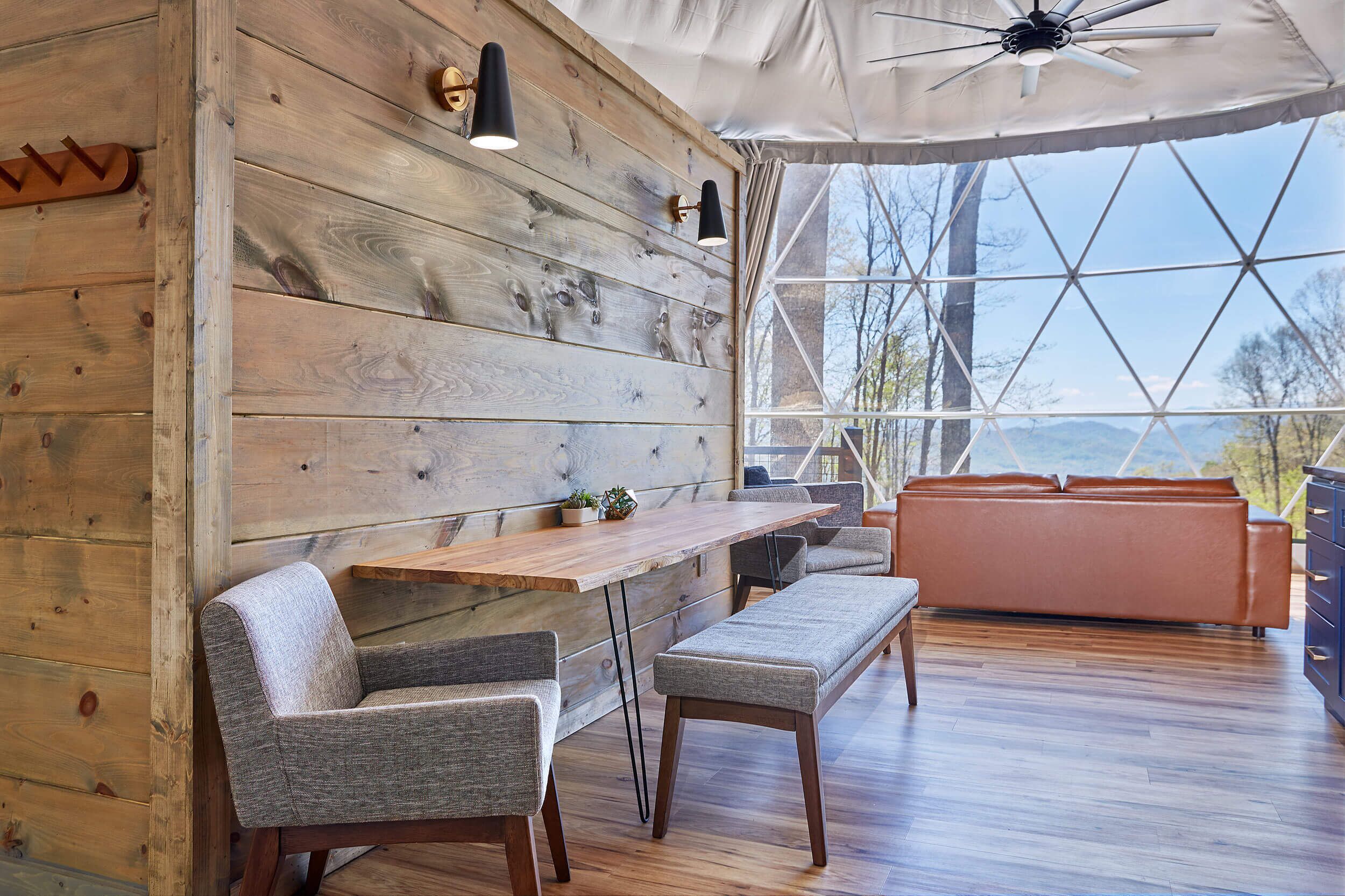 A modern interior with a wooden wall, a wooden dining table, and a sofa.