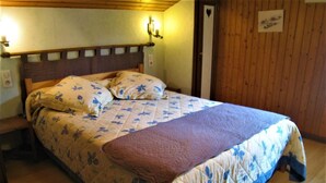 A bed with a floral quilt, a wooden headboard, and a bedside table with a lamp.