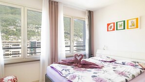 Une chambre d’hôtel avec un lit, une chaise, une fenêtre avec des rideaux et une vue sur une région montagneuse.