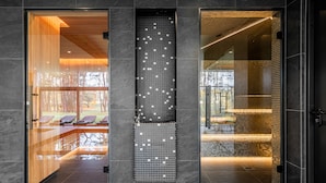 A modern interior with a glass door leading to a seating area, a tiled wall with a geometric pattern, and a well-lit interior space.