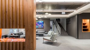 A modern interior with a wooden reception desk, a sofa, a chair, and a staircase.