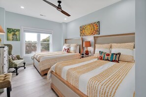 A bedroom with two beds, a ceiling fan, artwork, and a window. - Walk to beach sleeps 8 (Carolina Beach)