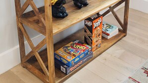 Ett konsolbord i trä med en inramad välkomstskylt, en flaska, glas och en Jenga-låda.