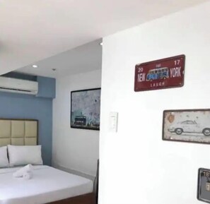Cozy retreat with a neatly made bed, headboard, and wall-mounted air conditioning unit.