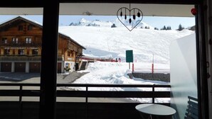 Un balcón con vistas a una montaña nevada y un edificio de madera con un letrero que dice "BAR RESTAURANT le Champois".