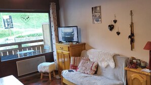 Una sala de estar acogedora con un sofá, un televisor y un taburete pequeño.