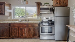 A kitchen with wooden cabinets, stainless steel appliances, and a window with a view of trees.