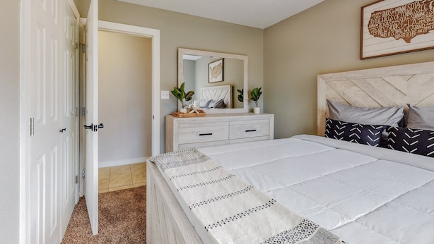 A bedroom with a bed, a dresser, a mirror, and a ceiling fan.