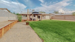A residential backyard with a covered patio, a lawn, and a house with a garage.