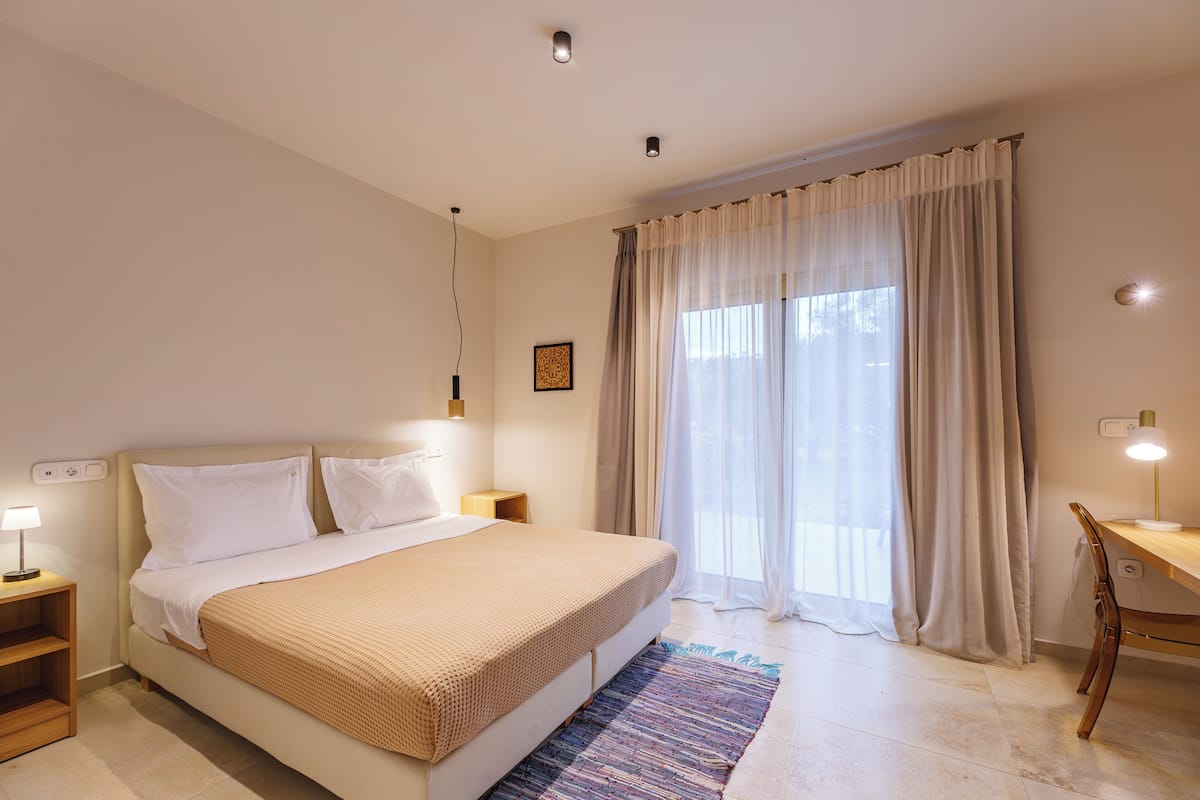 Een slaapkamer met een bed, nachtkastjes, een bureau en een stoel.
