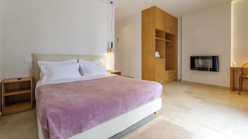 A modern bedroom with a large bed, wooden wardrobe, and a TV mounted on the wall.