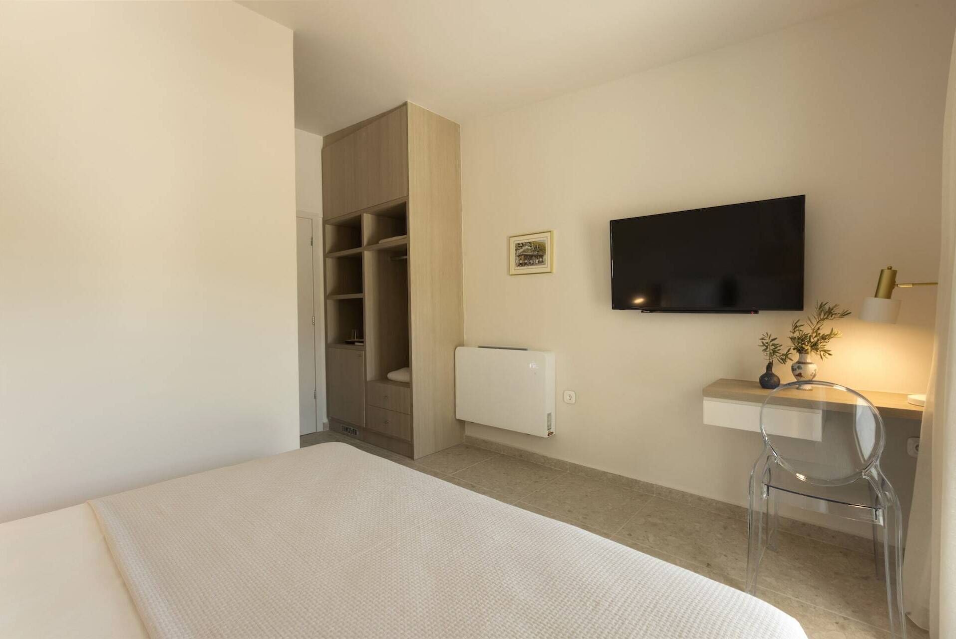 Una camera da letto con un letto, una scrivania con una sedia, una TV e un armadio.
