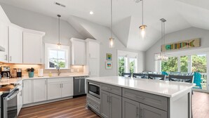 Een moderne keuken met witte kasten, een groot eiland en een eetgedeelte met uitzicht.