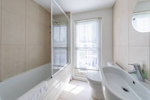 A modern bathroom with a shower, toilet, and sink. - Stylish 2 Bedroom Home in Islington With Garden (London)