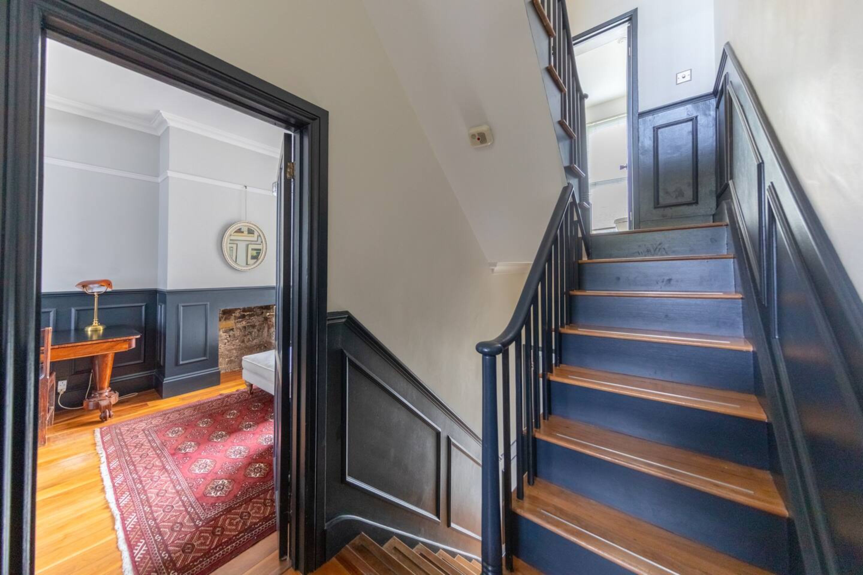 A staircase with dark railings and wooden steps, leading to an upper floor.