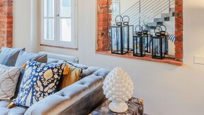 A living room with a grey sofa, a decorative white vase, and a black and gold trunk. - Casa Lucky, Romantic Modern 3 bedrooms Penthouse inside the Walls of Lucca (Lucca)