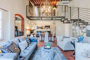 A spacious living area with a high ceiling, a staircase, and a kitchen in the background. - Casa Lucky, Romantic Modern 3 bedrooms Penthouse inside the Walls of Lucca (Lucca)