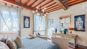 A bedroom with a bed, a chair, a vanity with a mirror, and artwork on the walls. - Casa Lucky, Romantic Modern 3 bedrooms Penthouse inside the Walls of Lucca (Lucca)