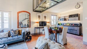 A spacious living area with a sofa, a dining table set, a kitchen with modern appliances, and a staircase with glass railings. - Casa Lucky, Romantic Modern 3 bedrooms Penthouse inside the Walls of Lucca (Lucca)