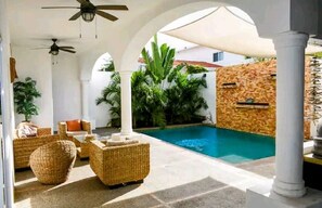 Relax by the serene pool surrounded by lush greenery and white columns.