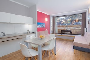A modern apartment with a kitchen, dining area, and a living room with a large window offering a city view. - Wifi, 50m from shops, swimming pool, sauna, tv, ski locker, 26m², Isola 2000 (Isola)