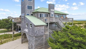 A multi-story wooden building with a 'ONE' sign on each level, featuring balconies and a staircase. - Oceanfront Home w/ Private Pool, Hot Tub, Private Beach Boardwalk. It's the One! (Avon)