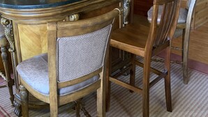 Interior de una cabaña de madera con una mesa de comedor, sillas, una barra y una escalera.