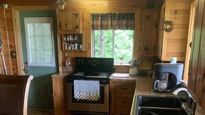 Cocina de cabaña de madera con estufa, pileta y cafetera.