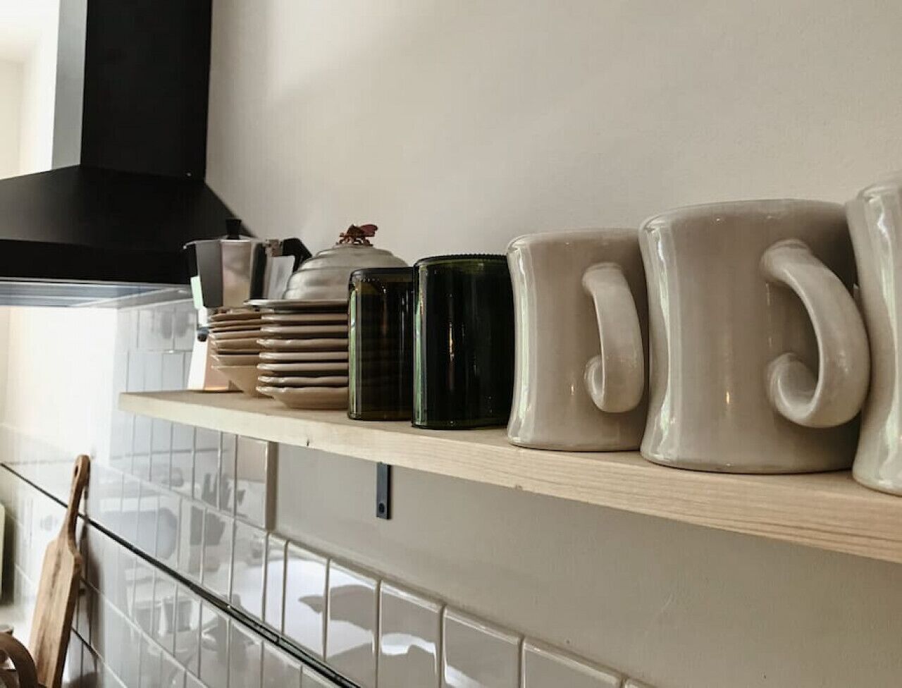 A kitchen shelf with various ceramic mugs and containers.