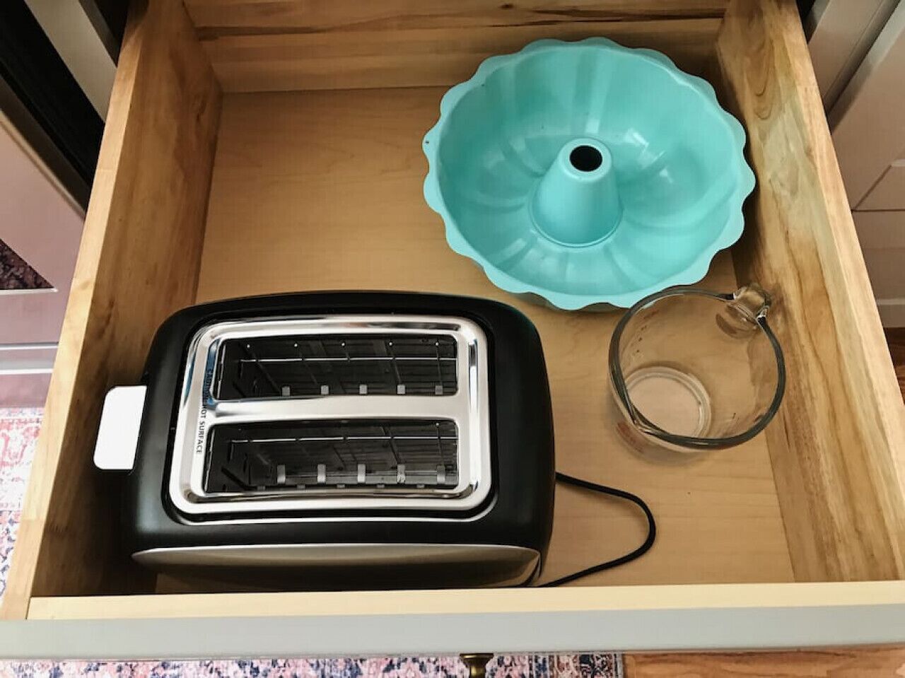 A drawer containing a toaster, a glass bowl, and a glass pitcher.
