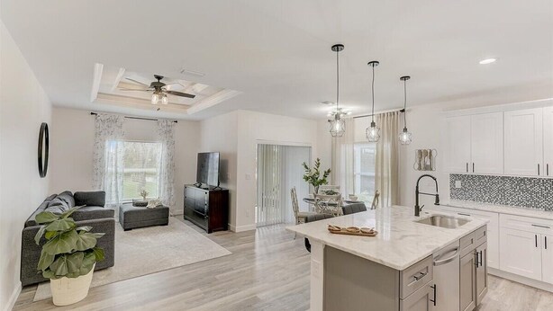 Una cocina moderna con una isla central, armarios blancos e iluminación colgante.