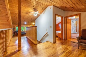 Un intérieur en bois avec un escalier, un ventilateur de plafond et une vue sur un espace extérieur.
