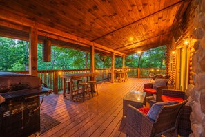 Une terrasse extérieure couverte, équipée d’un barbecue, de meubles en osier et d’un mur en pierre.