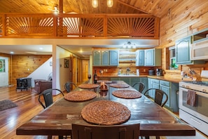 A wooden interior with a dining table, chairs, kitchen area, and a staircase.