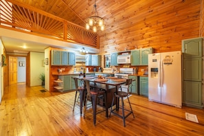 A wooden cabin interior with a dining area, kitchen, and a large wooden ceiling. - Fern Ridge Cabin - Hot Tub - 60 Acres with Trails! (Laurelville)