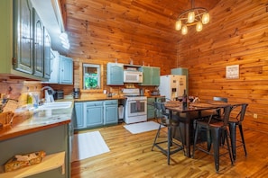 Une cuisine aux murs lambrés, comprenant un coin repas, des placards, un four à micro-ondes, un réfrigérateur et une machine à café.