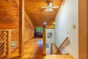 Un intérieur en bois avec un escalier, un ventilateur de plafond et une vue sur l’extérieur.