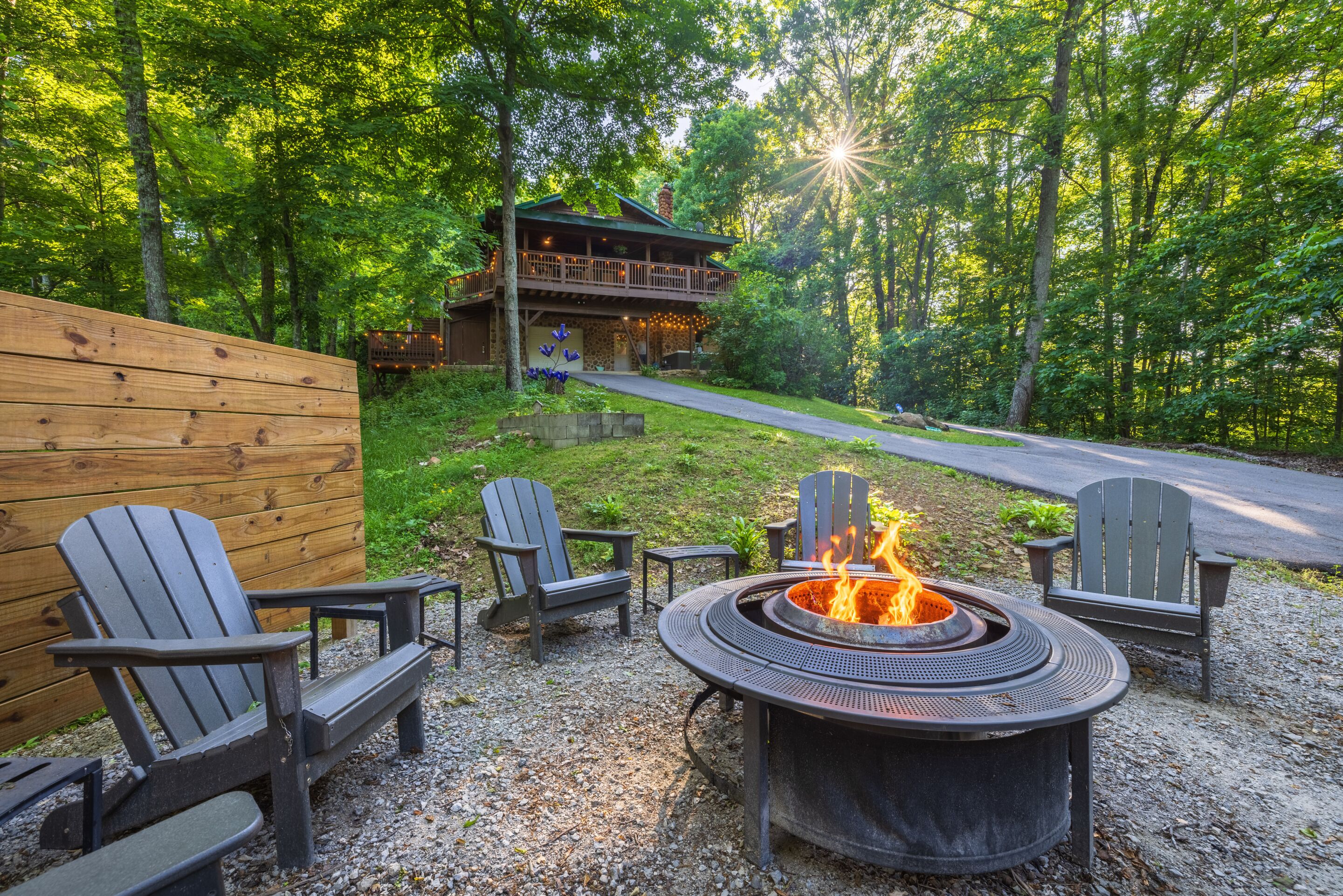 A wooden deck with Adirondack chairs, a fire pit, and a stone building with a balcony.