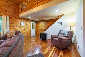A wooden interior with a sofa, armchair, and a heater.