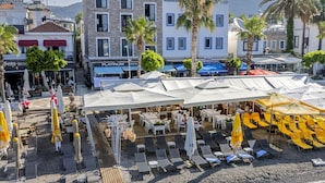 Zona de playa con mesas al aire libre, sombrillas y un edificio con un letrero que dice 'Platinum Restaurant'.