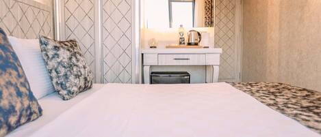 Habitación de hotel con una cama, una mesita de noche con lámpara, un espejo y una ventana.