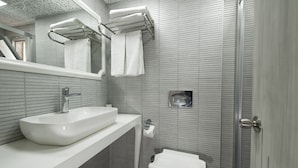 Un baño moderno con un lavamanos blanco, un inodoro y una zona de ducha.