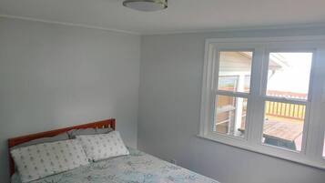 Een slaapkamer met een bed, een raam en een plafondlamp.