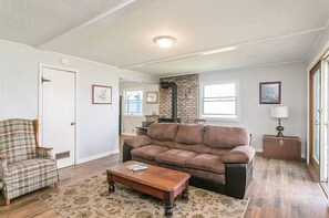 Ein Wohnzimmer mit einem braunen Ledersofa, einem karierten Sessel und einem Couchtisch aus Holz.