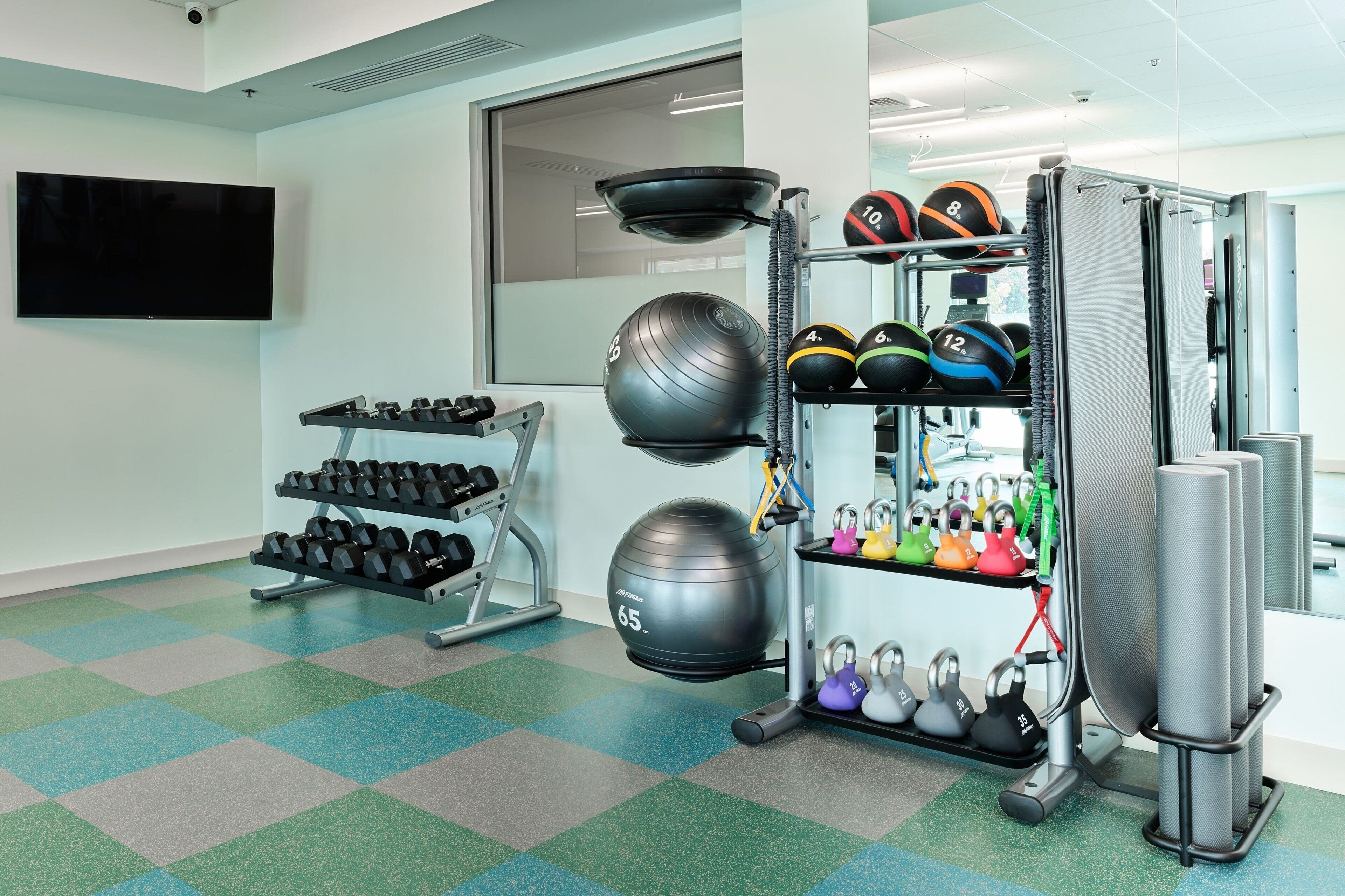 Un gimnasio con equipo de ejercicio, incluyendo mancuernas, balones medicinales y kettelbells.