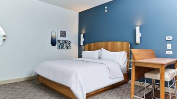 A modern hotel room with a wooden bed, a small desk, and a blue accent wall.