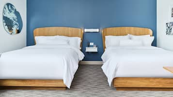 A hotel room with two beds, a nightstand, and a wall-mounted light fixture.