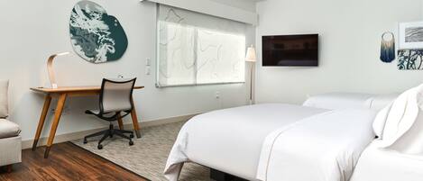 Una habitación de hotel con cama, escritorio, silla y un ventanal grande.